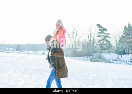Père donne piggyback ride pour enfant ensemble en hiver Banque D'Images