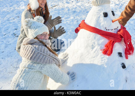 Girl s'appuie le Snowman en hiver avec sa famille et a l'amusement Banque D'Images