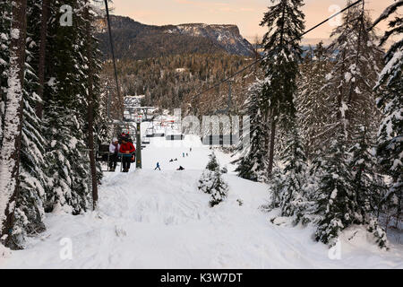 L'Italie, Trentin-Haut-Adige, la vallée de Non, les randonneurs sur le télésiège admirer paysage en hiver. Banque D'Images