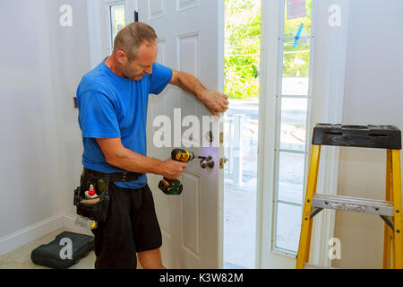 Installation d'un verrou sur la porte d'entrée de la main avec un tournevis pour l'homme installe bouton de porte. Banque D'Images