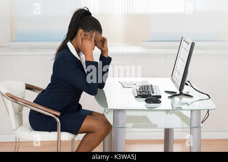 Jeune femme d'Afrique qui souffrent de maux de tête In Office Banque D'Images