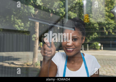 Femme africaine avec nettoyage vitre vitre de l'extérieur en caoutchouc Banque D'Images