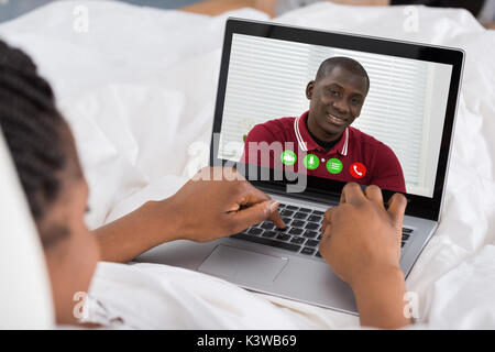 Jeune femme africaine le chat vidéo avec un homme On Laptop Banque D'Images