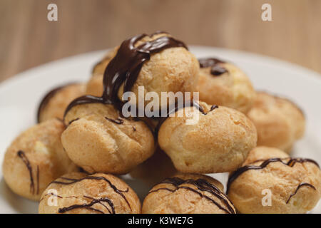 Profiteroles au gros plan sur la plaque de chocolat noir fin Banque D'Images