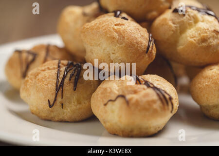 Profiteroles au gros plan sur la plaque de chocolat noir fin Banque D'Images