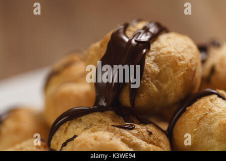 Profiteroles au gros plan sur la plaque de chocolat noir fin Banque D'Images