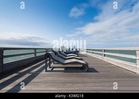 Les gens à prendre le soleil sur des chaises longues sur la jetée de heiligenhafen sur la mer baltique, Schleswig-Holstein, Allemagne Banque D'Images