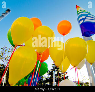 De nombreux ballons colorés lancé à partir de la les enfants heureux volant dans le ciel bleu Banque D'Images