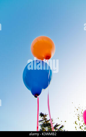 De nombreux ballons colorés lancé à partir de la les enfants heureux volant dans le ciel bleu Banque D'Images