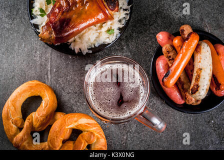 Sélection de cuisine allemande traditionnelle Oktoberfest. La bière, le jarret de porc au four, popcorn, réplique des saucisses, des bretzels. On a black sto Banque D'Images