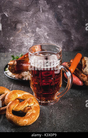 Sélection de cuisine allemande traditionnelle Oktoberfest. La bière, le jarret de porc au four, popcorn, réplique des saucisses, des bretzels. On a black sto Banque D'Images