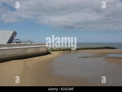 Plage de Porth Eirias à marée basse avec mur de mer et centre de sports nautiques et groyne rocheuse en arrière-plan à la baie de colwyn au nord du pays de galles Banque D'Images