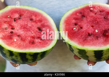 Un jeune homme est titulaire de deux moitiés de melon d'eau dans ses mains. Le concept d'une alimentation saine et le végétarisme. Banque D'Images