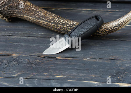 Petit couteau sur un fond en bois noir avec une corne de renne. Accessoires touristiques Banque D'Images