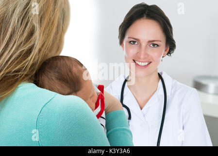 Close-up Mother Carrying Baby et Happy Female Doctor Banque D'Images