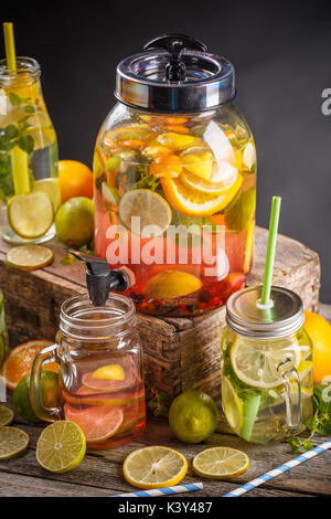 Boisson d'été rafraîchissante avec des baies rouges et des limes dans un pichet et verres sur la table en bois vintage Banque D'Images