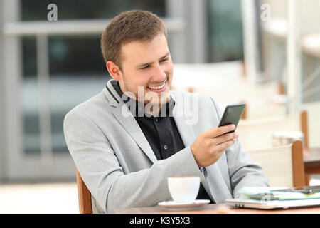 Seul l'homme exécutif lecture le contenu en ligne d'un téléphone portable assis dans un restaurant. Banque D'Images