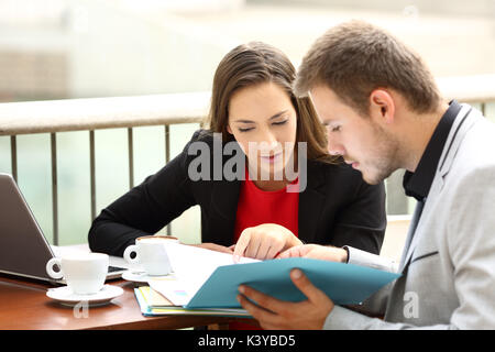 Deux cadres à l'analyse des documents de coworking assis dans un bar Banque D'Images