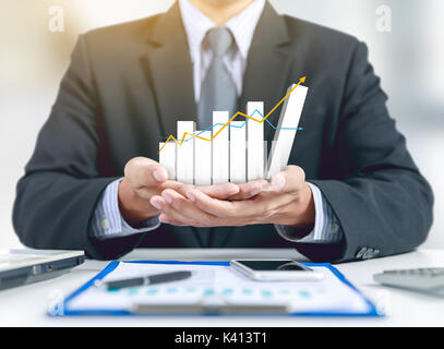 Businessman présent cultiver le graphique sur la main avec plan d'affaires, téléphone fixe et mobile Banque D'Images
