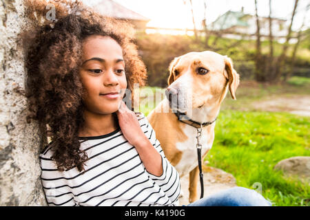 African American girl avec son chien dans le mur de béton. Banque D'Images