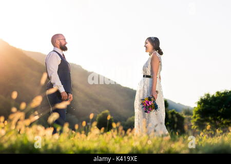 Mariée et le marié à l'autre dans le domaine au coucher du soleil Banque D'Images