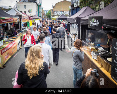 Brick Lane dimanche marché alimentaire - touristes et habitants de parcourir les stands de nourriture dans la rue Brick Lane dans l'East End londonien un dimanche matin Banque D'Images