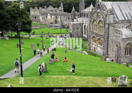 Les visiteurs les gens marcher sur la pelouse en été à l'extérieur de la cathédrale de St David's, Pembrokeshire, Pays de Galles UK KATHY DEWITT Banque D'Images