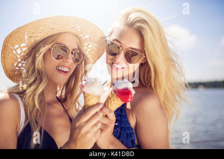 Une photo de deux belles femmes de manger de la crème glacée aux fraises crème et avoir du plaisir. Banque D'Images