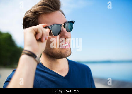 Une photo de jeune homme à lunettes en regardant le lac. Banque D'Images