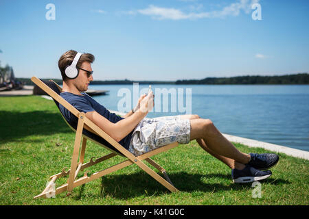 Une photo de jeune homme se détendre dans la chaise et d'écouter de la musique. Banque D'Images