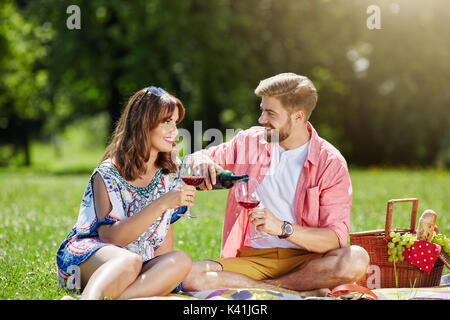 Une photo de jeunes couples célébrant leur anniversaire dans l'air frais. Ils sont de boire du vin rouge. Banque D'Images