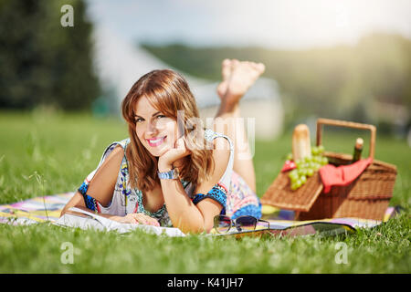 Une photo de jeunes, belle femme se détendre dans l'air frais. Elle ment sur la couverture et la lecture de livre. Banque D'Images