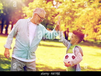 Vieil homme et garçon avec ballon de soccer en haut cinq Banque D'Images