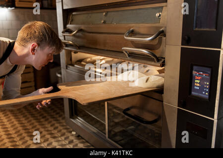 Baker de mettre la pâte au four à pain bakery Banque D'Images