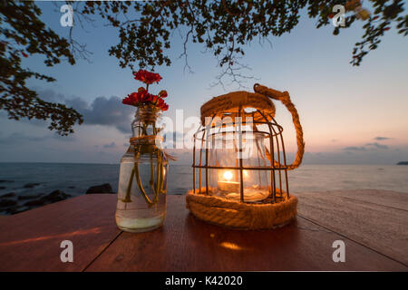Bougie sur une table au restaurant avec vue sur le coucher du soleil sur l'île de Koh Kood, Thaïlande Banque D'Images