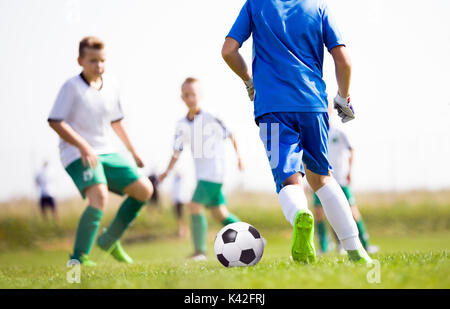 Les jeunes garçons jouant au football match de football sur terrain de sport. Enfants qui courent après le ballon de soccer. Les enfants des coups de match de football Banque D'Images