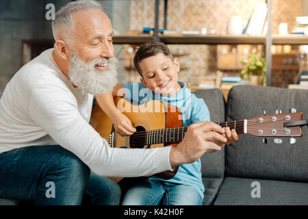 Grand-père aimant teaching grandson comment tenir la guitare Banque D'Images