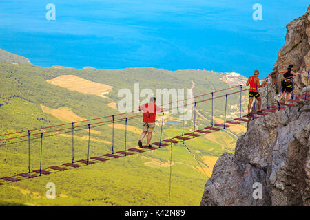 L'homme est de marcher le long d'un pont suspendu au-dessus de l'abîme. Yalta, la Crimée. La notion de risque et de danger. Banque D'Images