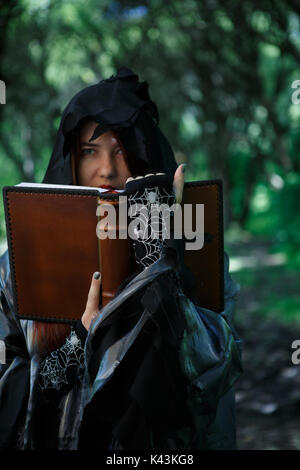 Photo de sorcière sort de lecture à partir de la réserve en forêt mystique Banque D'Images