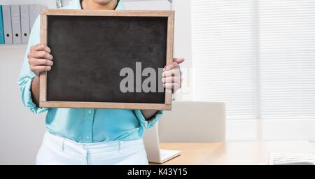 Digital composite of business woman holding blank card in office Banque D'Images