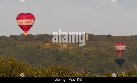 BATH, Royaume-Uni - 28 AUG 2017 Liveried montgolfières en face de Brown's Folly. Le rouge et le blanc les ballons servant au transport de personnes au-dessus de campagne dans le Somerset Banque D'Images