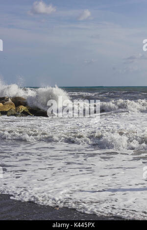 MARINA DI MASSA, ITALIE - 17 août 2015 : vague smash dans les rochers dans une journée ensoleillée avec une mer en Toscane Banque D'Images