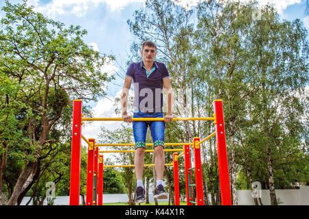 Jeune homme n'est pratiquer sur une barre horizontale dans le parc aux beaux jours d'été Banque D'Images