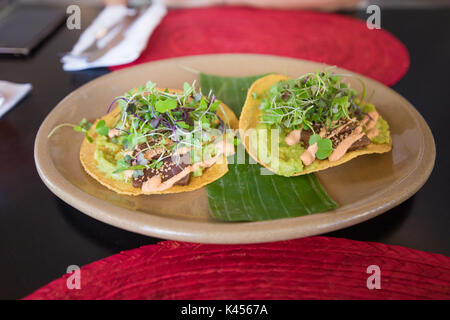 Deux tacos del pastor avec feuilles de cresson en plat de céramique sur tableau noir avec de la paille rouge sets de table in restaurant Banque D'Images