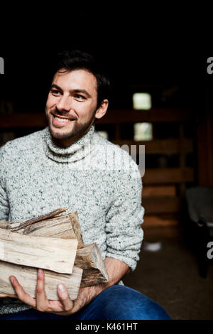 Grange, avec l'homme pull tricoté est transporter le bois, gai, half-portrait, Banque D'Images