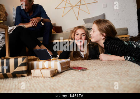 La période de Noël, deux jeunes filles se trouvent sur le tapis avec l'ordinateur tablette, rire Banque D'Images