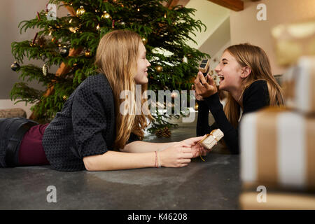 Deux jeunes filles en face de l'arbre de Noël, présente, la veille de Noël Banque D'Images