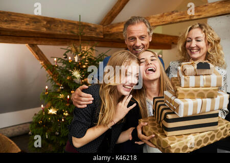 Les parents et leurs filles avec présente en face d'arbre de Noël, la moitié portrait Banque D'Images