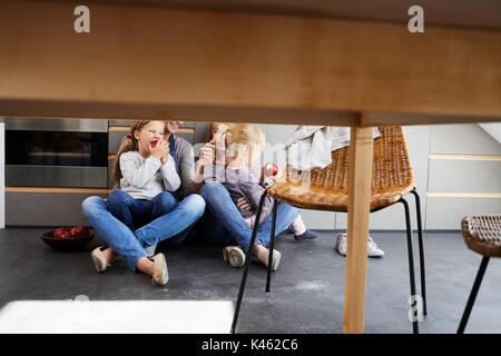 Grand-mère, la mère et les filles assis sur plancher de la cuisine, détail, table, chaise, Banque D'Images