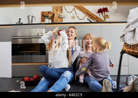 Grand-mère, la mère et les filles assis sur plancher de la cuisine, Banque D'Images